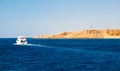 Beautiful snow-white yacht sails in the sea, into the distance. Rock in the background