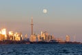 Beautiful soft pink colors at dusk with the full moon rising over the Toronto skyline and CN Tower