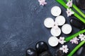 Beautiful spa background with massage pebble, green leaves, flowers and candles on black stone table from above. Aromatherapy.