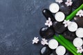 Beautiful spa background with massage pebble, green leaves, flowers and candles on black stone table top view. Aromatherapy. Royalty Free Stock Photo