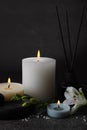 Beautiful spa composition with different care products and burning candles on dark grey table against black background Royalty Free Stock Photo