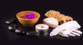 Beautiful spa composition with pink orchid on cup, stones and white gloves on black wooden table. Royalty Free Stock Photo