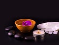 Beautiful spa composition with pink orchid on cup, stones and white gloves on black wooden table. Royalty Free Stock Photo