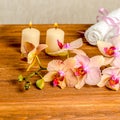 beautiful spa concept of blooming twig orchid flower, phalaenopsis, white towels and candles on wooden background, closeup Royalty Free Stock Photo