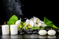 beautiful spa concept of blooming white orchid flower, phalaenopsis, green leaf with dew, smoke stick and candles on black zen st Royalty Free Stock Photo