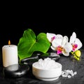 beautiful spa concept of white orchid flower, phalaenopsis, green leaf with dew, sea salt and candle on black zen stones, close up Royalty Free Stock Photo