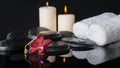 Beautiful spa concept of zen stones with drops, purple orchid (phalaenopsis), candles with reflection on water, white towels Royalty Free Stock Photo