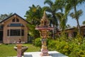 A beautiful spiritual house with decorations and incense bowls is standing in front of a residential building in Thailand in