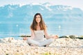 Beautiful spiritual woman meditating by the lake