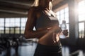 A beautiful sport woman holding water bottle in her hands at the gym under morning sunlight, fitness and healthy lifestyle, Royalty Free Stock Photo
