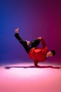 Beautiful sportive boy dancing hip-hop in stylish clothes on colorful gradient background at dance hall in neon light. Royalty Free Stock Photo
