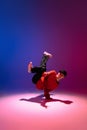 Beautiful sportive boy dancing hip-hop in stylish clothes on colorful gradient background at dance hall in neon light. Royalty Free Stock Photo