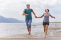 Beautiful sportive couple running on the water along the wild beach Royalty Free Stock Photo