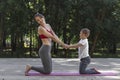 Beautiful sportive mom and little son do yoga in the morning park Royalty Free Stock Photo