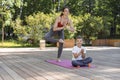 Beautiful sportive mom and little son do yoga in the morning park together Royalty Free Stock Photo