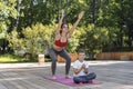 Beautiful sportive mom and little son do yoga in the morning park together Royalty Free Stock Photo