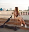 Beautiful sports girl rides a scooter on a summer park on a sunny day. Royalty Free Stock Photo