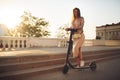Beautiful sports girl rides a scooter on a summer park on a sunny day. Royalty Free Stock Photo