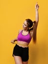 Beautiful sports woman measure her waist with hand pointing finger up on yellow background Royalty Free Stock Photo