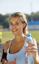 Beautiful sportsgirl in a stadium. Woman with bootle of water.