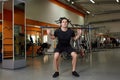 Beautiful sportsman in the black sportwear with bar flexing muscles in gym.