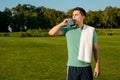 Beautiful sportsman drinking water on the lawn.