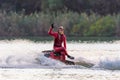 Beautiful sportsman woman on jet ski making freestyle, splashing and showing v-sign in