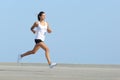 Beautiful sportswoman running with the sky in the background