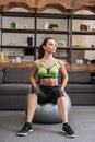Beautiful sportswoman sitting on fitness ball at home and Royalty Free Stock Photo
