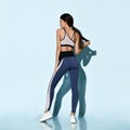 Beautiful sportswoman in sportswear working out doing stretching sports exercises on light blue Royalty Free Stock Photo