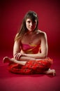 Beautiful sporty fit yogi woman practices yoga asana Agni Stambhasana - Fire Log pose on the red background. studio shot