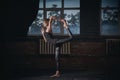 Beautiful sporty fit yogi woman practices yoga asana Natarajasana - Lord Of The Dance pose in the dark hall Royalty Free Stock Photo