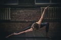 Beautiful sporty fit yogini woman practices yoga asana in the dark hall Royalty Free Stock Photo