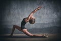 Beautiful sporty fit yogini woman practices yoga asana Virabhadrasana 1 - warrior pose 1 in the dark hall Royalty Free Stock Photo