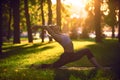 Beautiful young woman practices yoga asana Virabhadrasana 1 - warrior pose 1 in the park at sunset Royalty Free Stock Photo