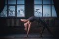 Beautiful sporty fit yogini woman practices yoga asana Wild Thing Pose in the dark hall Royalty Free Stock Photo