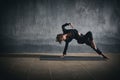 Beautiful sporty fit yogini woman practices yoga asana Wild Thing Pose in the dark hall Royalty Free Stock Photo
