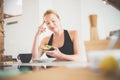 Beautiful sporty fit young pregnant woman having a healthy snack in home kitchen. Healty lifestyle concept. Royalty Free Stock Photo