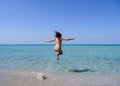 Beautiful sporty girl in a colorful bikini jumping into the turquoise water of a beautiful beach Royalty Free Stock Photo