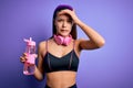 Beautiful sporty girl doing sport using headphones drinking bottle of water to refreshment stressed with hand on head, shocked Royalty Free Stock Photo