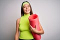 Beautiful sporty girl doing sport wearing sportswear holding yoga mat over white background with a happy face standing and smiling Royalty Free Stock Photo