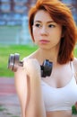 Beautiful sporty red-haired girl goes in for sports in the street with a metal dumbbell Royalty Free Stock Photo