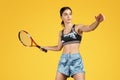Beautiful sporty young woman tennis player ready to shot the ball with red racquet over yellow background. Royalty Free Stock Photo