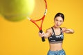 Beautiful sporty young woman tennis player shot the ball with red racquet over yellow background. Royalty Free Stock Photo