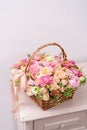 Flowers arrangement with various of colors in wicker basket on pink table. beautiful spring bouquet. bright room, white Royalty Free Stock Photo