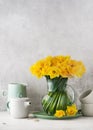 Beautiful spring floristic arrangement yellow daffodil flowers in a vintage glass jug.