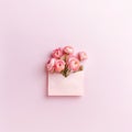Beautiful spring flowers and paper envelope on pink background. Flat lay, top view. Flowers background Royalty Free Stock Photo