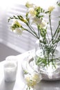 Spring freesia flowers and candles on table in room Royalty Free Stock Photo