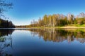 Beautiful spring landscape. Reflection of the blue cloudless sky and trees in the calm water of a forest lake Royalty Free Stock Photo