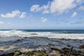 a beautiful spring landscape at Sandy Beach with blue ocean water, silky brown sand, rocks covered in green algae, crashing waves Royalty Free Stock Photo